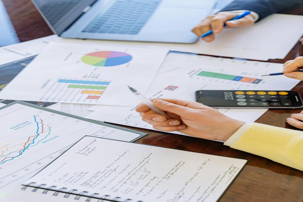 People analyzing financial charts and data in a business meeting with a calculator and growth charts.